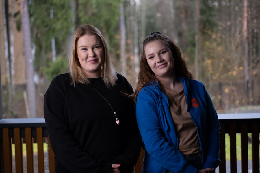 Kaksi Onnikotien työntekijää seisoo ulkona terassilla ja nojaa kaiteeseen.